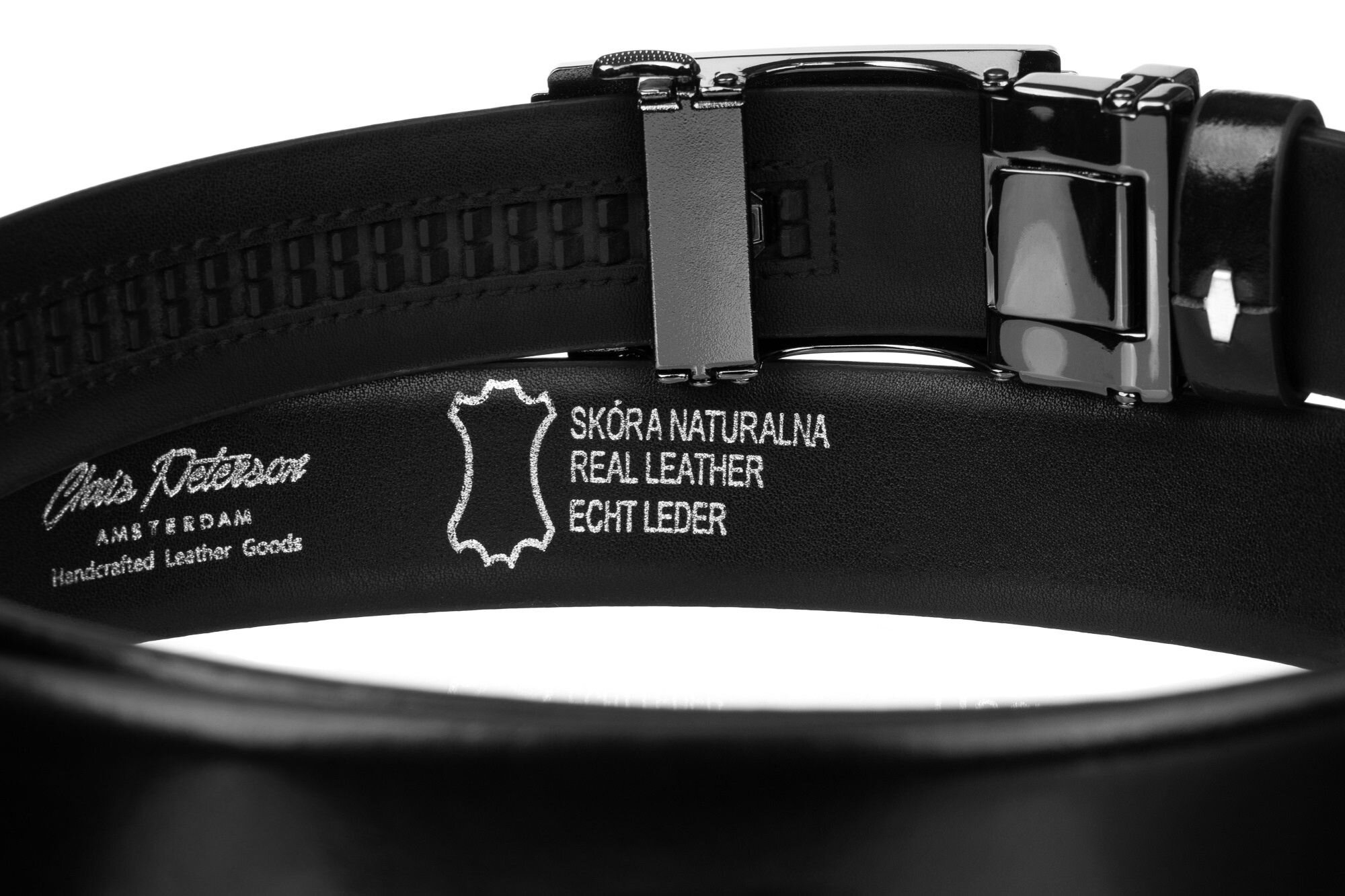 Czarny skórzany pasek z metalową klamrą, na wewnętrznej stronie widoczny jest napis: \'Chris Peterson Amsterdam Handcrafted Leather Goods\' oraz \'SKÓRA NATURALNA REAL LEATHER ECHT LEDER\'.