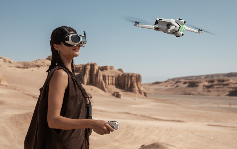 Osoba w goglach VR steruje dronem latającym na tle pustynnego krajobrazu z formacjami skalnymi.