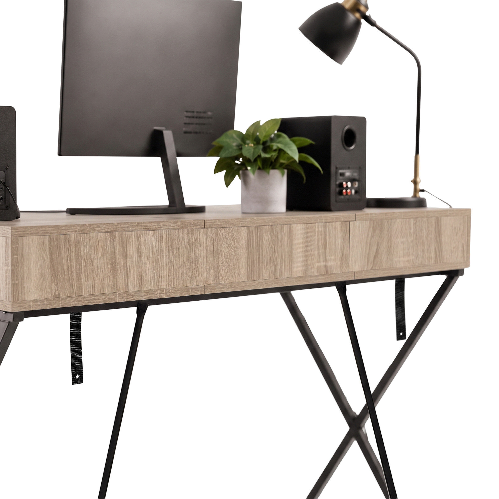 Biurko w stylu industrialnym z blatem w kolorze dębu Sonoma, wyposażone w czarne nogi w kształcie krzyża. Na biurku znajdują się monitor, lampa, głośnik i roślina w doniczce.