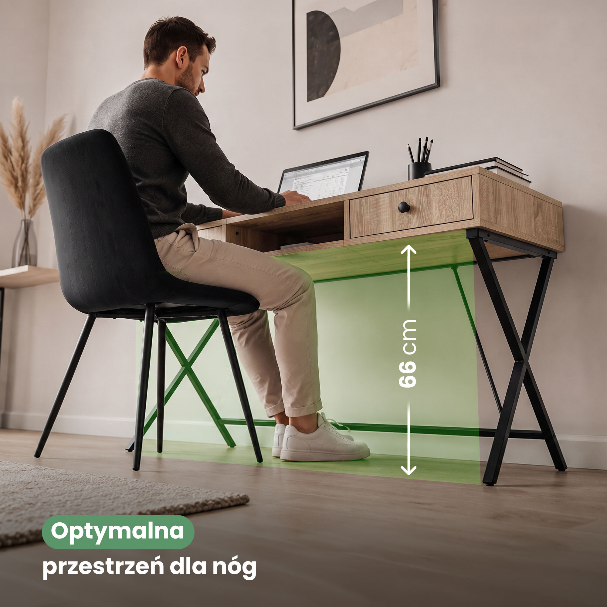 Mężczyzna siedzi przy biurku z dwiema szufladami i czarnymi nogami, pracując na laptopie. Na obrazie widoczny jest tekst: \'Optymalna przestrzeń dla nóg\' oraz \'66 cm\'.