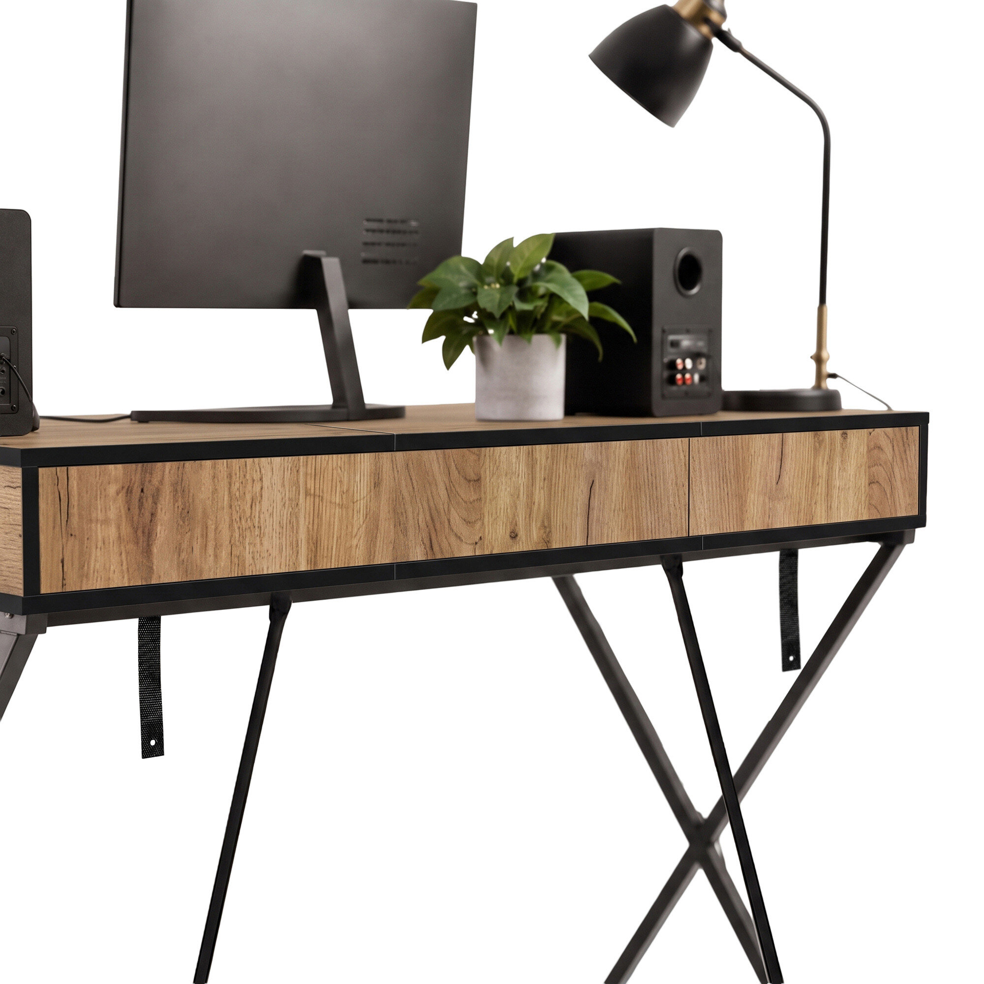 Biurko o industrialnym designie z blatem w kolorze dębu i czarnymi nogami w kształcie krzyża. Na blacie znajduje się monitor, roślina w doniczce, głośnik i lampa biurkowa.