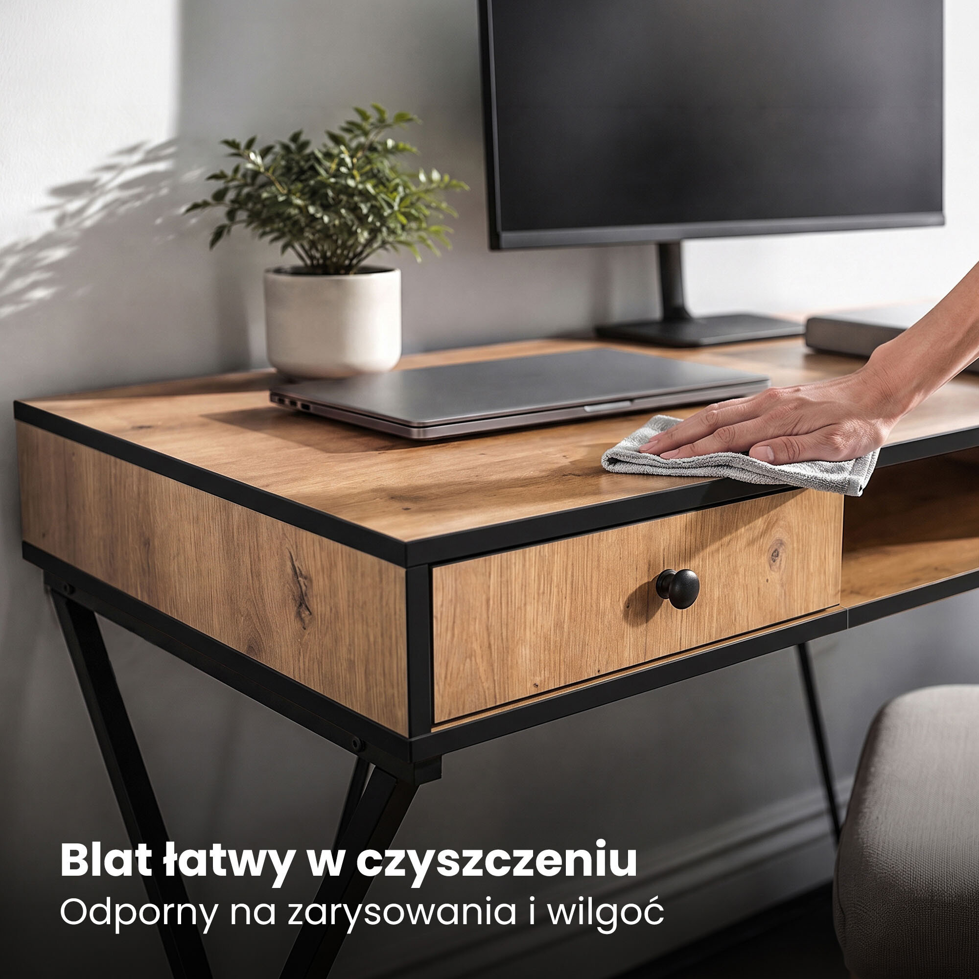Na zdjęciu widoczne jest biurko z drewnianym blatem i czarnymi nogami, na którym stoi monitor i laptop. Tekst na obrazie: \'Blat łatwy w czyszczeniu, Odporny na zarysowania i wilgoć\'.