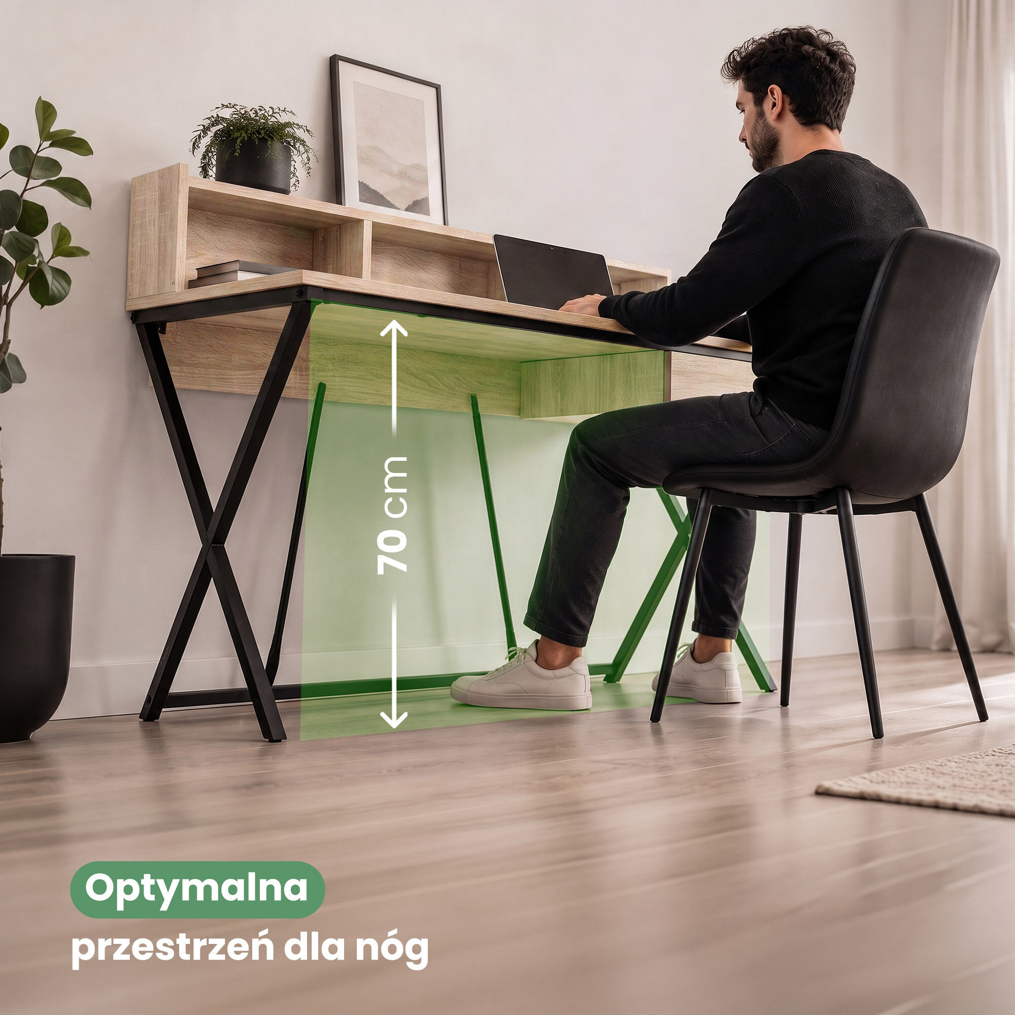 Osoba siedzi przy biurku z czarnymi nogami i blatem w kolorze dębu Sonoma, na którym stoi laptop. Na obrazie widoczny jest tekst: \'Optymalna przestrzeń dla nóg\' oraz oznaczenie wysokości 70 cm.