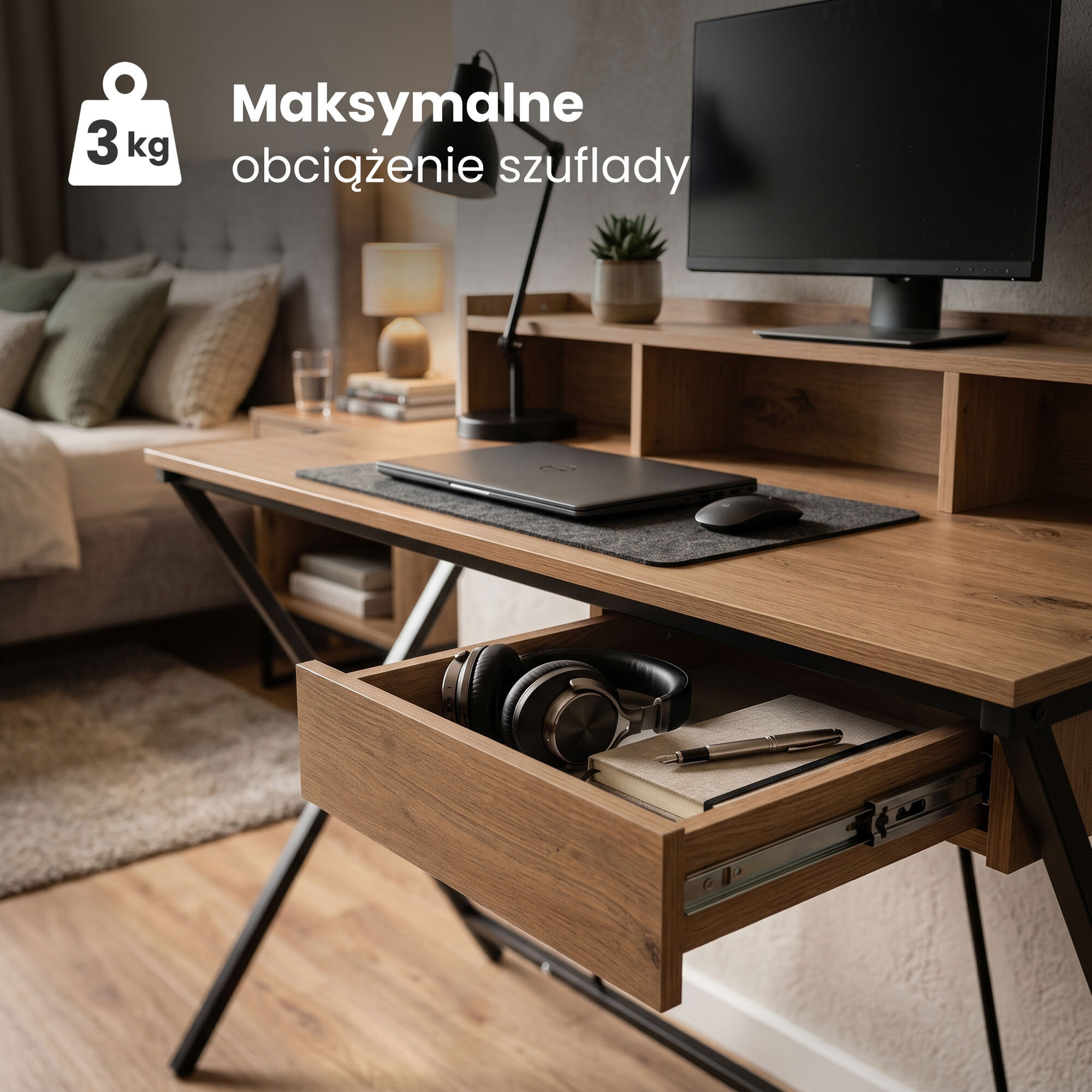 Biurko w stylu industrialnym z otwartą szufladą, w której znajdują się słuchawki, notes i długopis. Na biurku stoi monitor, laptop i lampka, a w tle widoczna jest część pokoju z łóżkiem i poduszkami. Tekst na obrazie: \'Maksymalne obciążenie szuflady 3 kg\'.
