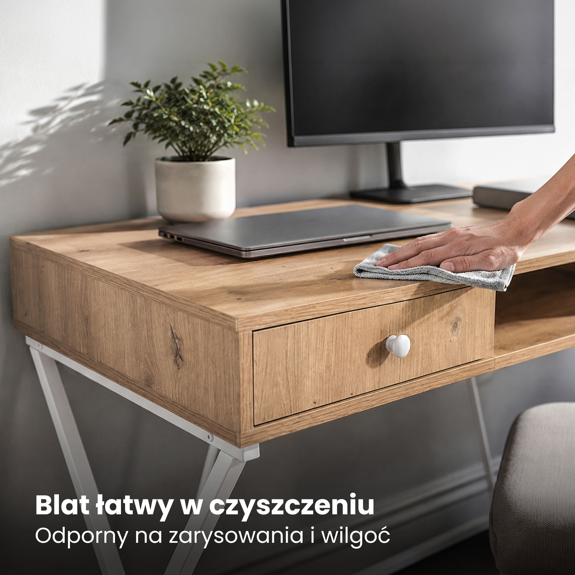 Na zdjęciu widoczne jest biurko z drewnianym blatem, na którym stoi monitor i laptop. Tekst na obrazie: \'Blat łatwy w czyszczeniu, Odporny na zarysowania i wilgoć\'.