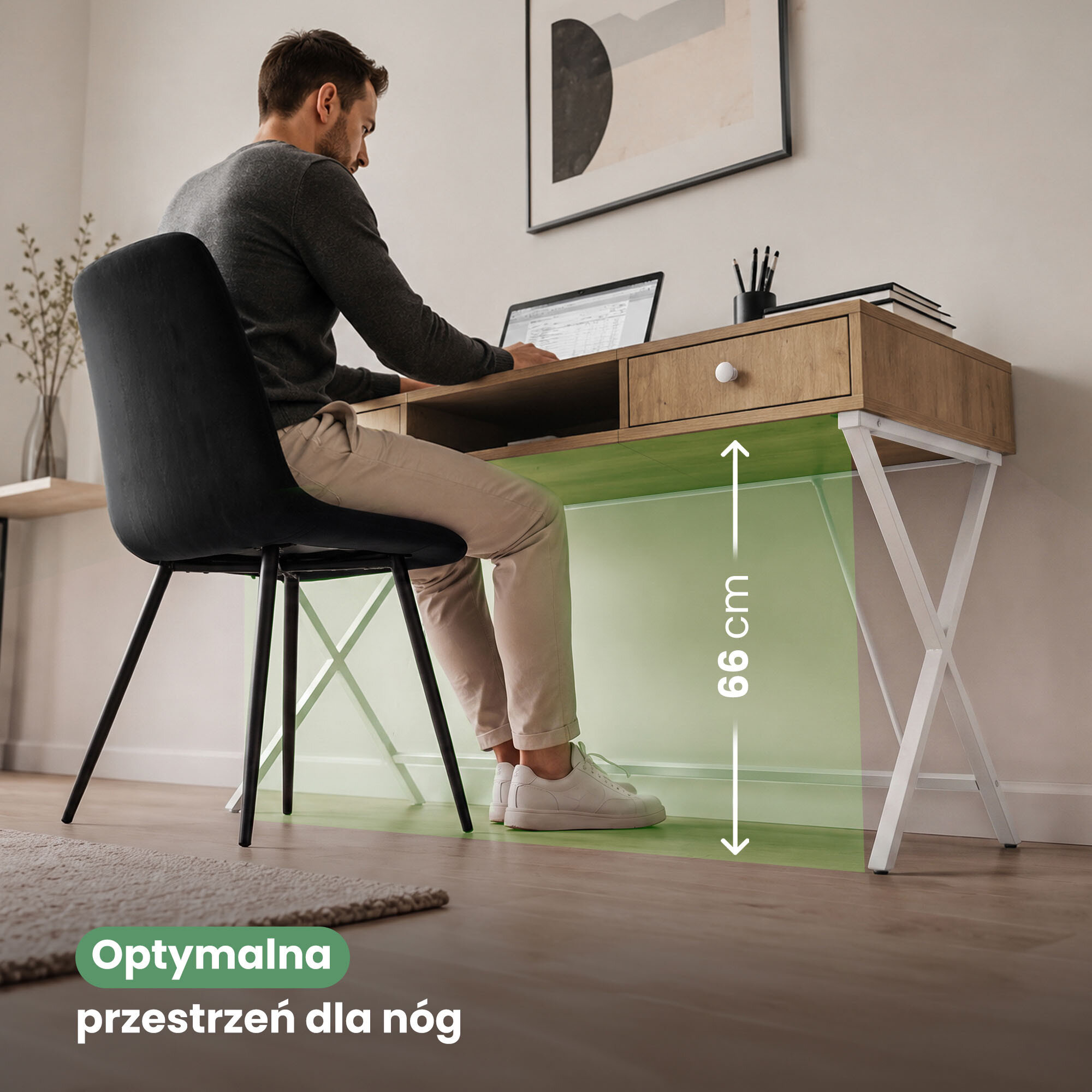 Mężczyzna siedzi przy biurku z dwiema szufladami i białymi nogami, pracując na laptopie. Na obrazie widoczny jest tekst: \'Optymalna przestrzeń dla nóg\' oraz oznaczenie wysokości 66 cm.