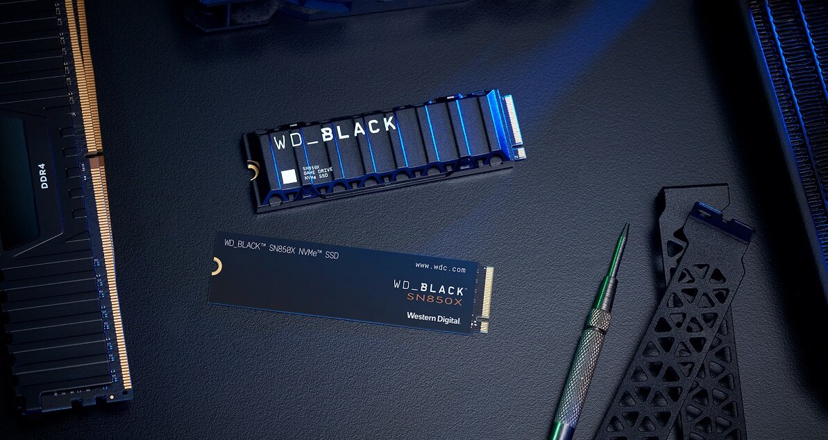 Na ciemnym tle leży dysk SSD z napisem \'WD_BLACK SN850X NVMe SSD\' oraz radiator z napisem \'WD_BLACK\'. Obok znajduje się narzędzie i element o trójkątnym wzorze.