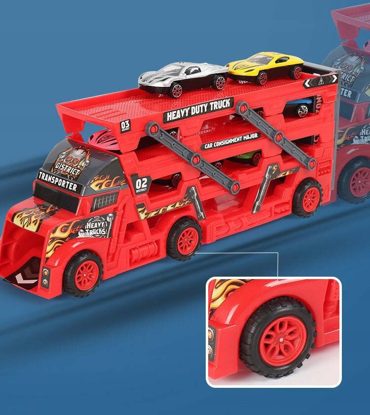 Czerwona ciężarówka z napisem \'HEAVY DUTY TRUCK\' na górnym poziomie, przewożąca dwa małe samochodziki. Na ciężarówce widoczne są również napisy \'TRANSPORTER\', \'02 DISTRICT\', \'03 DISTRICT\' oraz \'CAR CONSIGNMENT MAJOR\'.