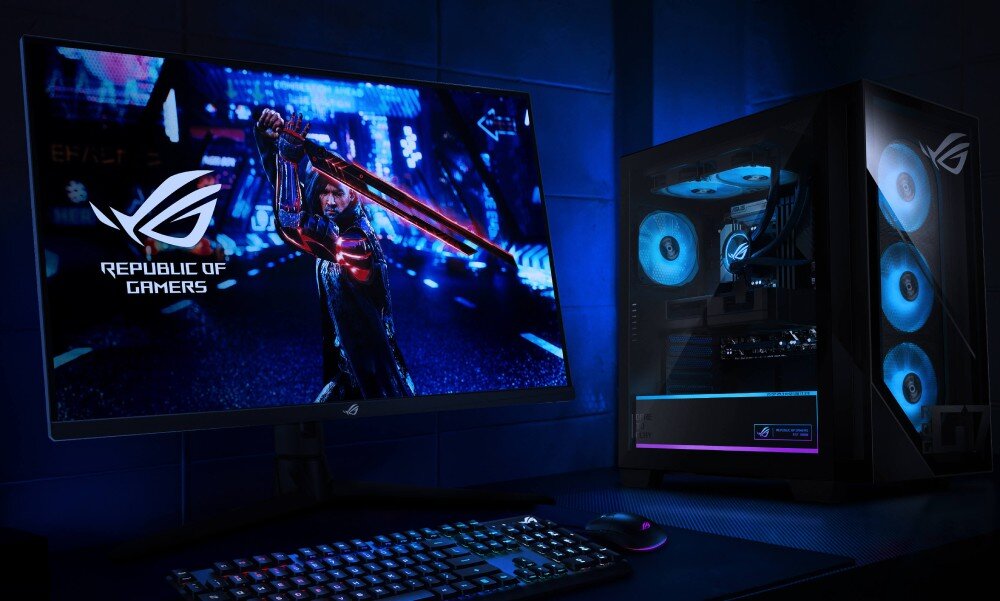 Komputer ASUS ROG G700TF-07265F421W Stanowisko z dużym monitorem wyświetlającym scenę z gry i obok stojącym komputerem w szklanej obudowie z niebieskim podświetleniem wentylatorów, styl