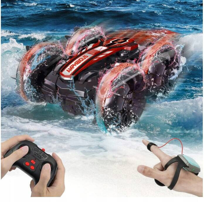 Zdalnie sterowany samochód amfibia porusza się po wodzie, a na jego powierzchni widoczny jest napis \'AMPHIBIOUS\'. Obok znajdują się dłonie trzymające pilot i opaskę do sterowania gestami.