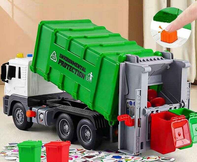 Zielona zabawkowa ciężarówka śmieciarka z napisem \'ENVIRONMENTAL PROTECTION\' na boku, z otwartą tylną klapą i kolorowymi pojemnikami na śmieci. W prawym górnym rogu widoczny jest palec naciskający pomarańczowy przycisk.