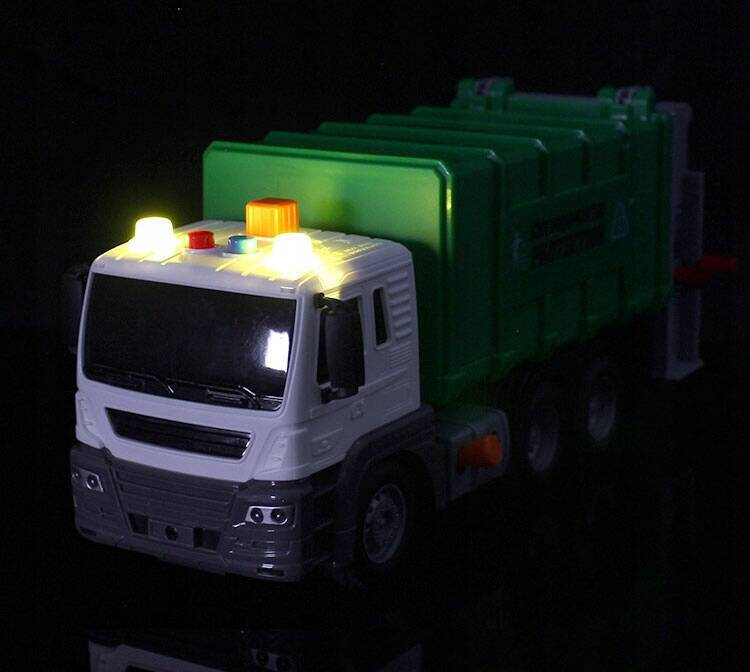 Zabawka ciężarówka śmieciarka z białą kabiną i zieloną naczepą, z włączonymi światłami na dachu. Na naczepie widoczny jest napis \'RECYCLING TRUCK\'.