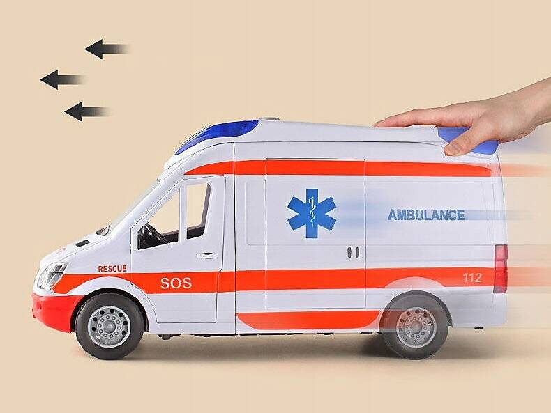 Zabawka w kształcie karetki pogotowia z napisem \'AMBULANCE\', \'SOS\', \'RESCUE\' i numerem \'112\'. Karetka jest biała z czerwonymi i niebieskimi elementami, a obok widoczna jest ręka sugerująca ruch pojazdu.