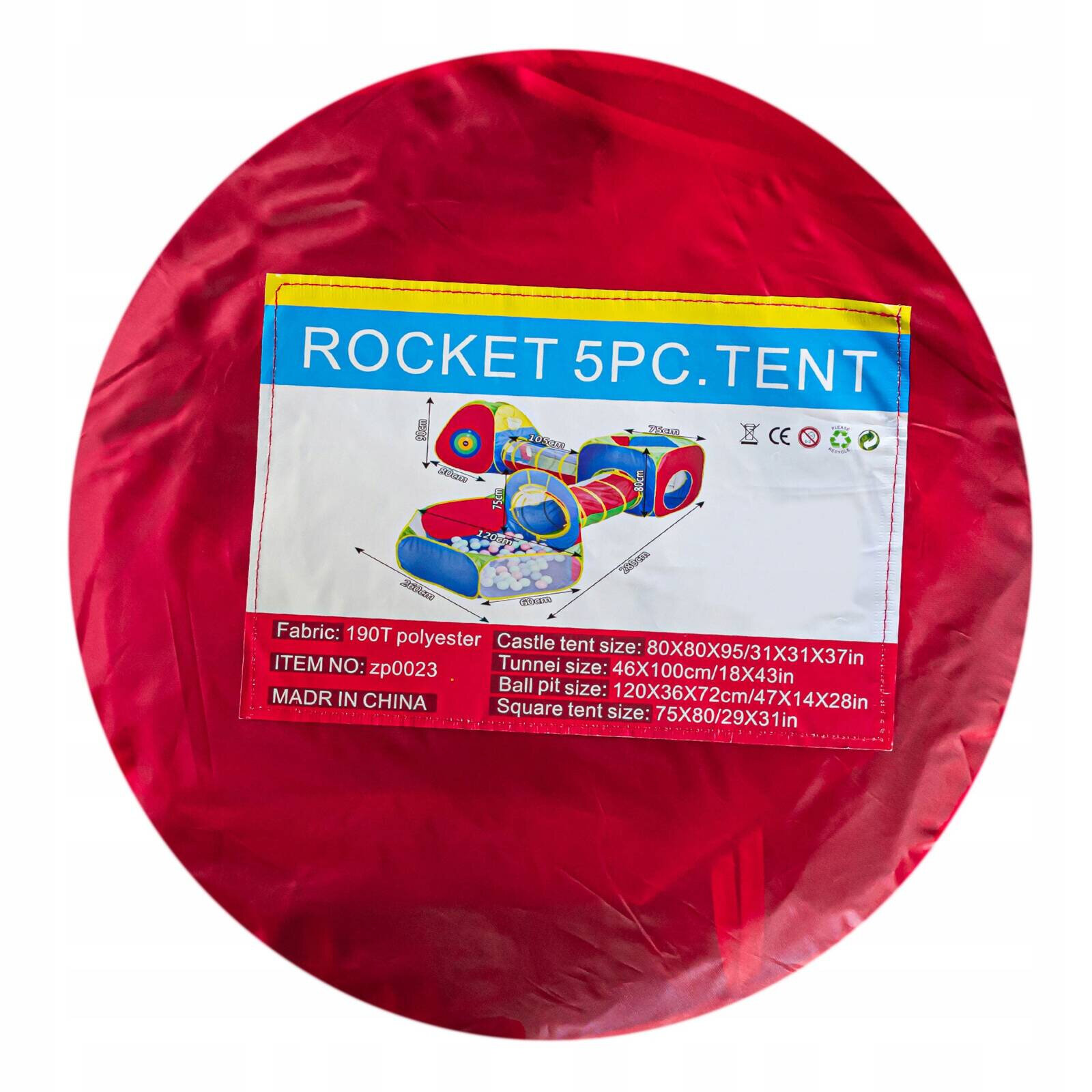Czerwony okrągły pokrowiec z etykietą przedstawiającą zestaw namiotów dla dzieci z tunelami i suchym basenem. Na etykiecie widnieje tekst: \'ROCKET 5PC. TENT\', wraz z wymiarami poszczególnych elementów i informacją \'Fabric: 190T polyester, ITEM NO: zp0023, MADE IN CHINA\'.