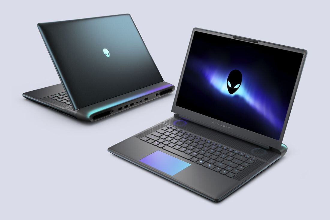 Na obrazie widoczne są dwa laptopy z logo przedstawiającym głowę kosmity. Jeden laptop jest otwarty, ukazując klawiaturę i ekran z grafiką, drugi jest zamknięty, pokazując tylną część obudowy.