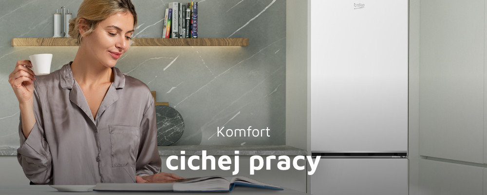 Osoba w szarej koszuli trzyma filiżankę, stojąc obok białej lodówki z logo beko. Na obrazie widoczny jest tekst: \'Komfort cichej pracy\'.