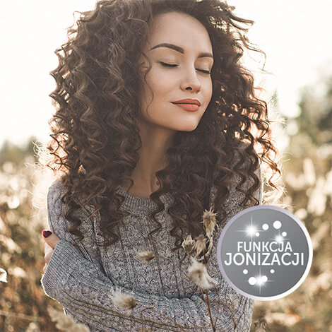 Kobieta z kręconymi włosami stoi na tle pola, obok widoczny jest okrągły symbol z napisem \'FUNKCJA JONIZACJI\'.