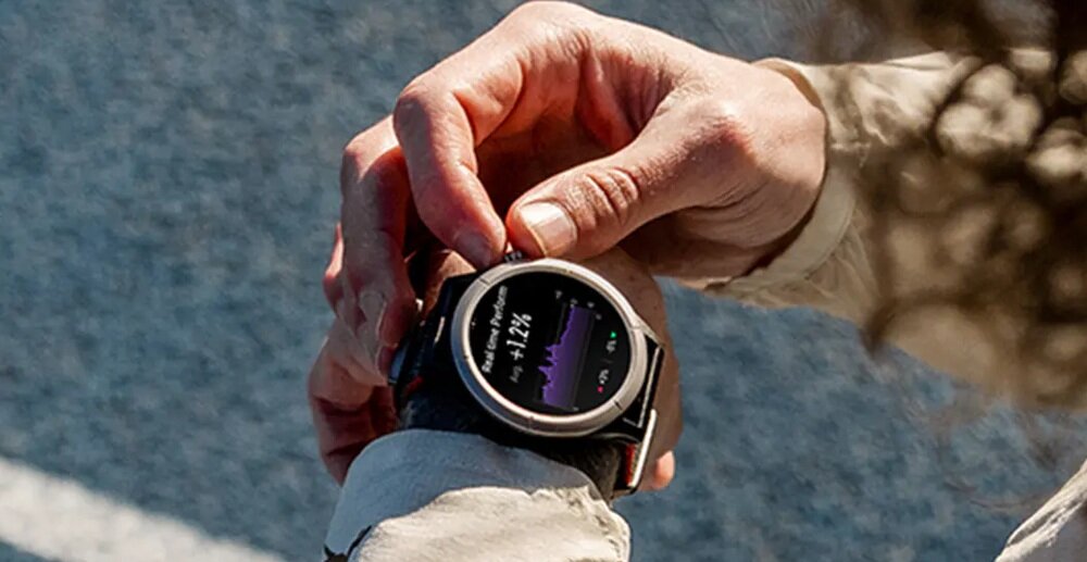Osoba obsługuje smartwatch z okrągłym wyświetlaczem, na którym widoczny jest wykres i liczba \'+1.24%\'.