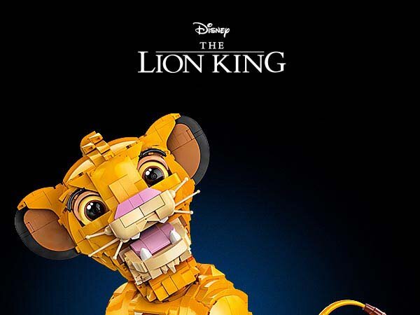 Na obrazie widoczna jest figurka młodego Simby zbudowana z klocków, na tle ciemnego tła. U góry znajduje się tekst: \'Disney THE LION KING\'.