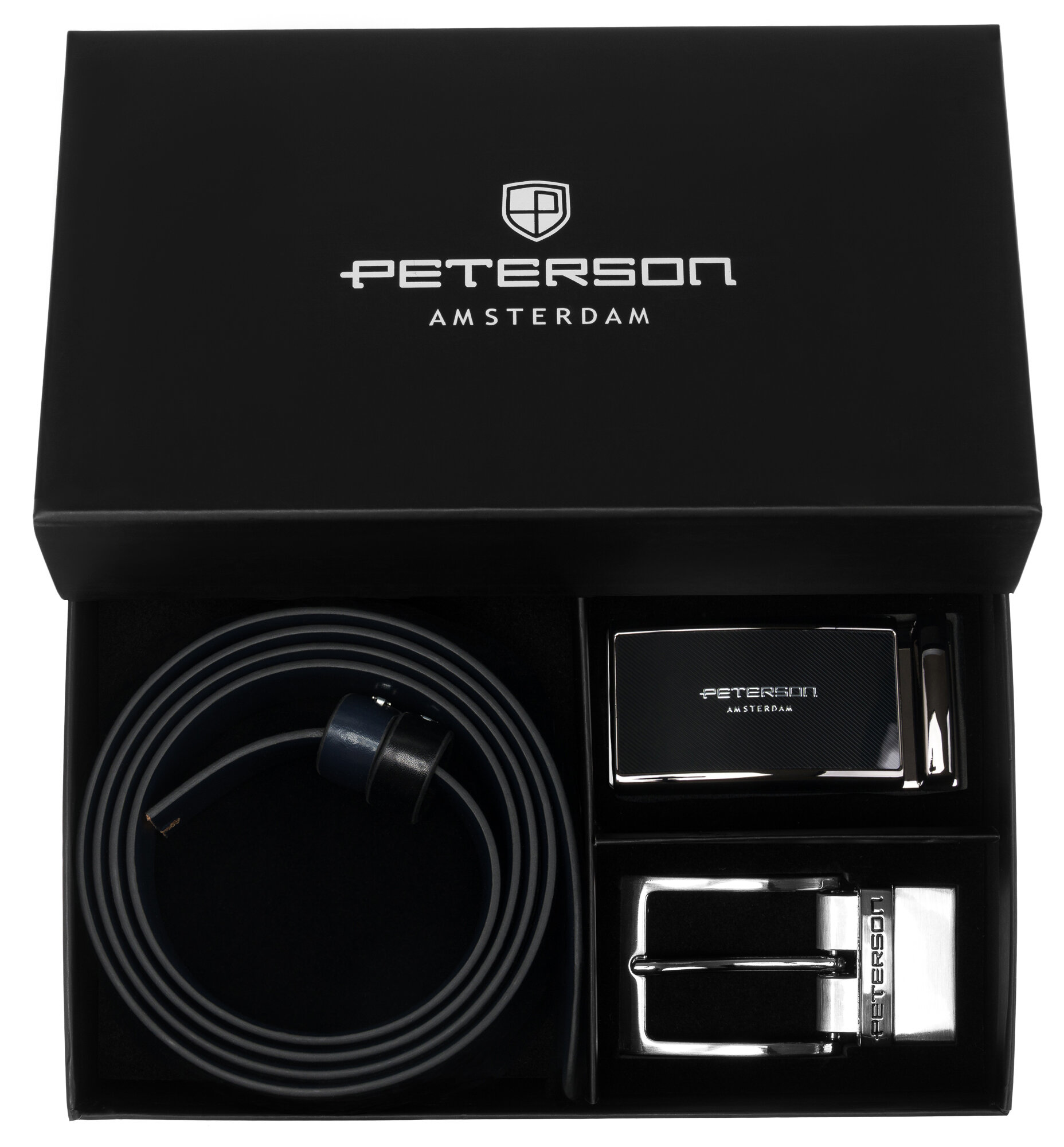 Czarny zestaw prezentowy zawiera skórzany pasek oraz dwie klamry. Na wieczku pudełka widnieje napis \'PETERSON AMSTERDAM\'.