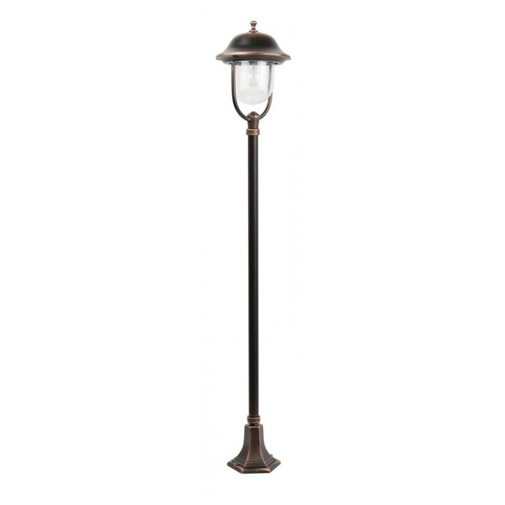 Stojąca lampa zewnętrzna w kolorze patyny miedzi z przezroczystym kloszem i ozdobnym daszkiem. Lampa ma prosty, smukły trzon zakończony szeroką podstawą.