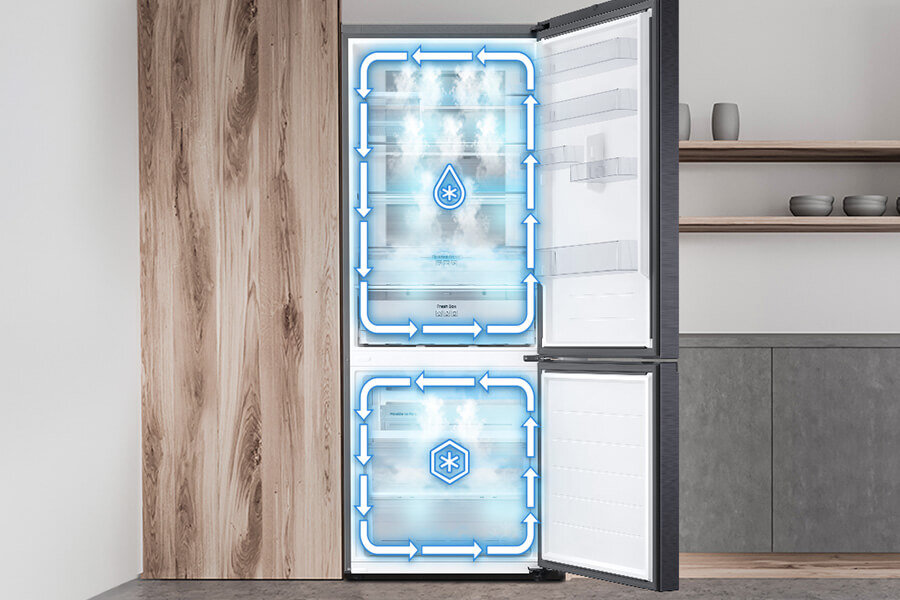 Two Cooling Plus - Samsung lodówka - Media Expert Otwarta lodówka z widocznymi niebieskimi strzałkami i symbolami wskazującymi na system chłodzenia. W tle znajduje się drewniana szafka i półki z naczyniami.