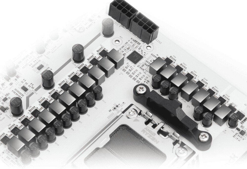 Zbliżenie na fragment płyty głównej z widocznymi elementami elektronicznymi, takimi jak kondensatory i złącza zasilania. Na płycie widoczny jest napis \'ASRock\'.