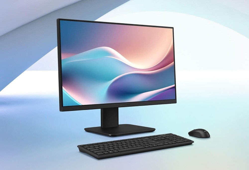 Komputer All in One ASUS V440VAT-BPD036W Komputer typu All in One z czarną obudową, dopasowaną klawiaturą oraz myszką komputerową, zaprezentowany na jasnoniebieskim, geometrycznym tle z widoczną na ekranie grafiką przedstawiającą pastelowe fale, opis