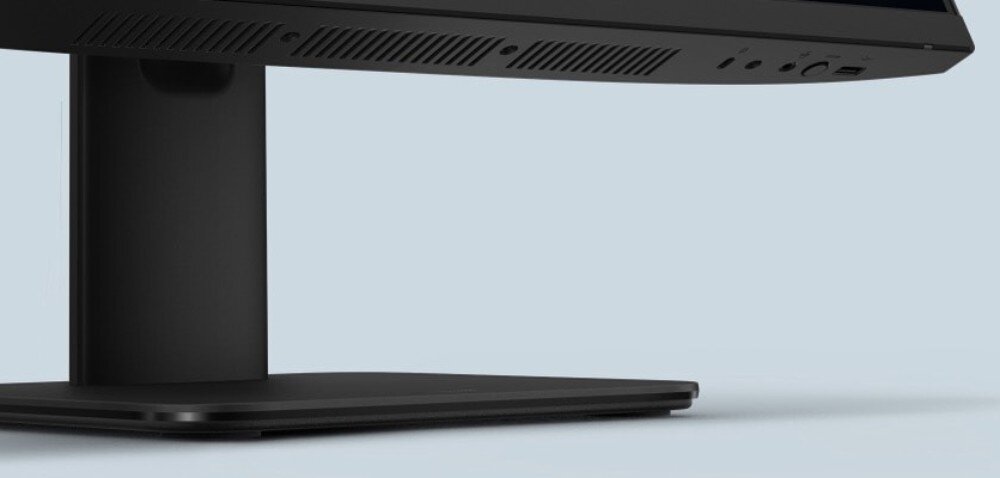 Komputer All in One ASUS V440VAT-BPD036W Zbliżenie na dolną część czarnej obudowy komputera oraz jego prostokątną podstawę, z widocznymi otworami wentylacyjnymi i portami złącz po prawej stronie na jasnym tle, łączność bezprzewodowa, porty