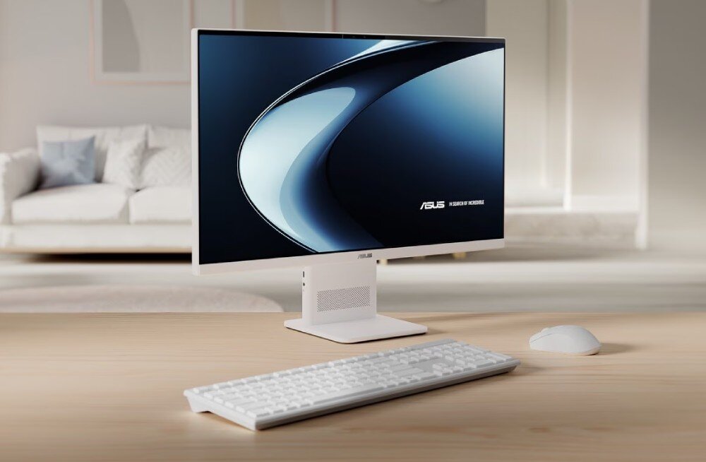 Na drewnianym biurku znajduje się komputer All in One z białą klawiaturą i myszką. Na ekranie widoczne jest logo ASUS oraz napis \'ExpertBook Series\'.