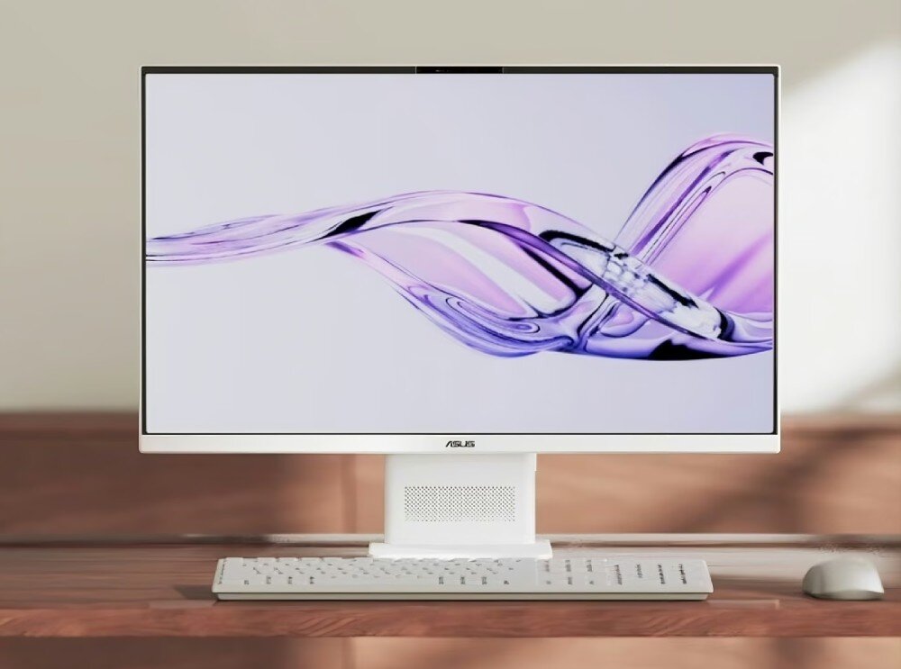 Na obrazie widoczny jest komputer All in One marki ASUS z dużym ekranem, na którym wyświetlany jest abstrakcyjny wzór w odcieniach fioletu. Pod ekranem znajduje się klawiatura, a na obudowie widoczne jest logo ASUS.