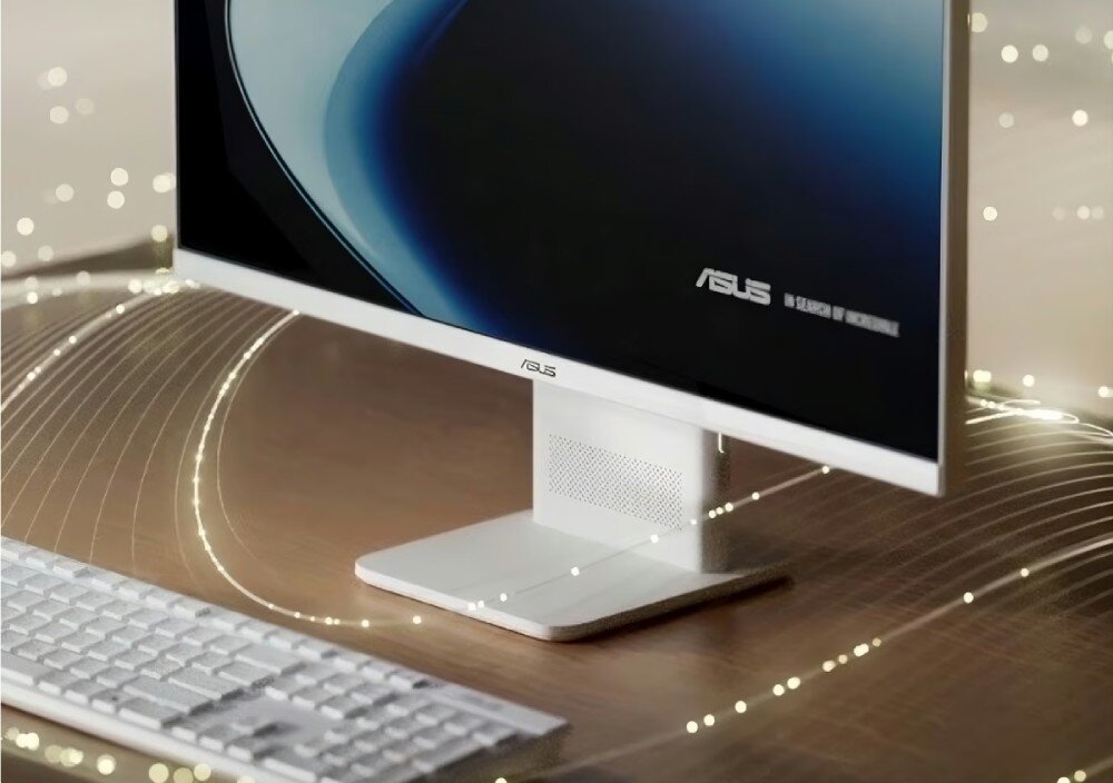 Na obrazie widoczny jest komputer All in One z logo ASUS na ekranie i podstawie. Obok znajduje się klawiatura na drewnianym biurku, a w tle widać delikatne świetlne linie.