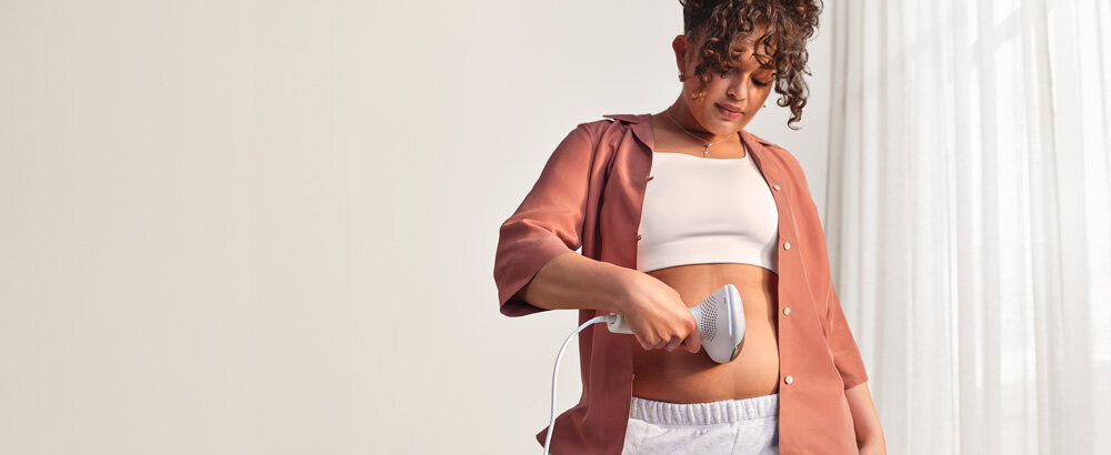 Kobieta depilująca włosy na brzuchu depilatorem Philips Lumea.