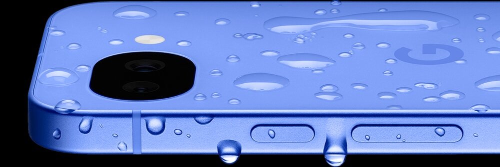 Zbliżenie na jasnofioletowy smartfon z widocznymi kroplami wody na obudowie. Na powierzchni znajduje się logo w kształcie litery \'G\'.