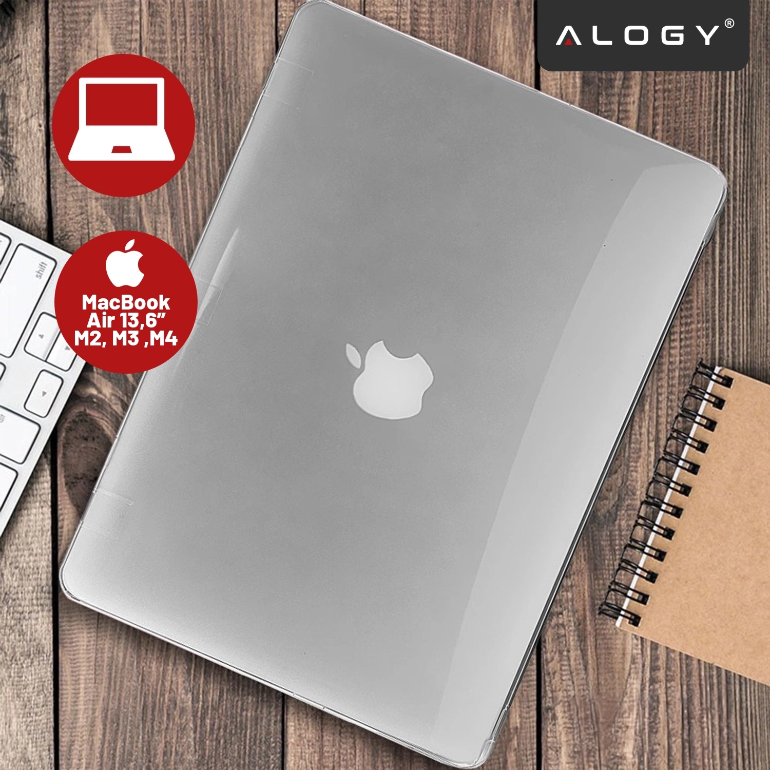 Na drewnianym tle leży przezroczyste etui na laptopa z widocznym logo w kształcie jabłka. W prawym górnym rogu znajduje się logo \'ALOGY\', a obok etui widoczna jest klawiatura i notatnik spiralny.