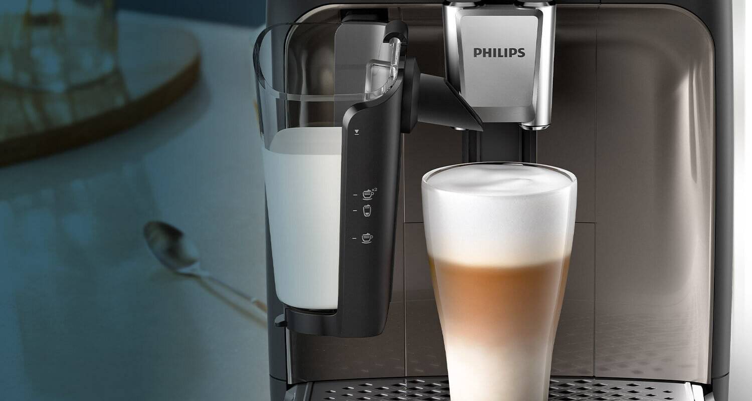 Ekspres do kawy z logo PHILIPS przygotowuje kawę z mleczną pianką w szklance. Obok znajduje się pojemnik na mleko z oznaczeniami funkcji.