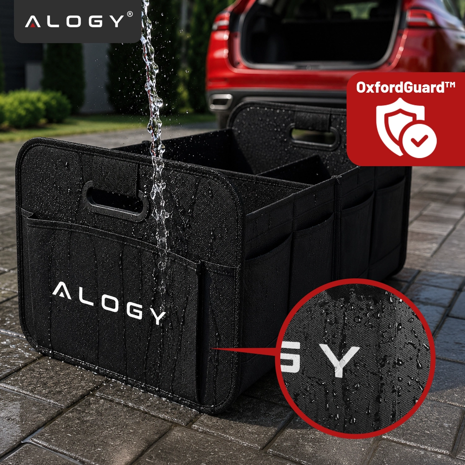 Czarny organizer do bagażnika samochodu z logo \'ALOGY\', na którym widać strumień wody. W tle otwarty bagażnik czerwonego samochodu oraz logo \'OxfordGuard™\'.