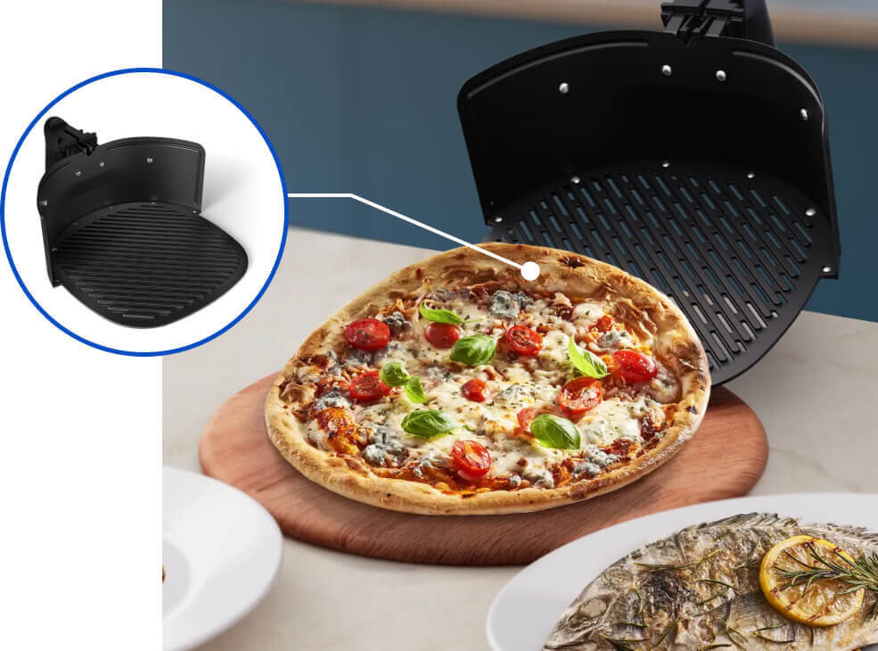 Na obrazie widoczna jest pizza na drewnianej desce oraz grillowana ryba na talerzu. W tle znajduje się otwarta frytkownica beztłuszczowa z widocznym rusztem, a w powiększeniu pokazany jest jej czarny, żebrowany wkład.