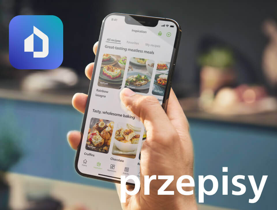 Osoba trzyma smartfon z aplikacją wyświetlającą przepisy kulinarne, takie jak \'Rainbow lasagna\' i \'Cruffins\'. W tle widoczne jest rozmyte wnętrze kuchni, a na obrazie znajduje się duży napis \'przepisy\'.