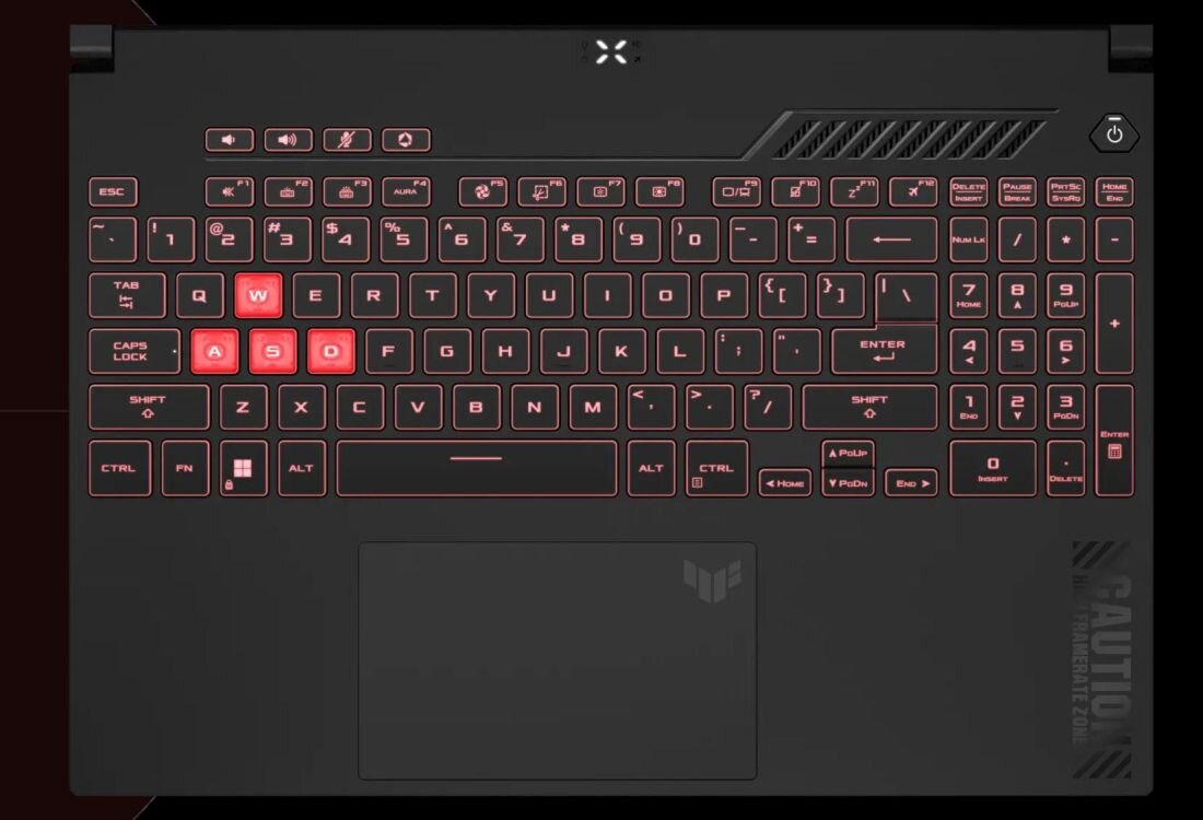 Klawiatura laptopa z podświetleniem w kolorze czerwonym, z wyróżnionymi klawiszami W, A, S, D. Na obudowie widoczne jest logo w kształcie litery X oraz napis \'CAUTION\'.