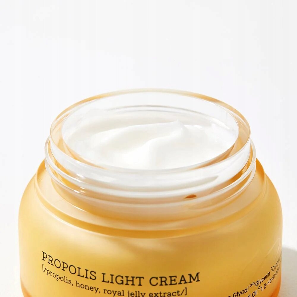 Otwarty słoik z kremem o białej konsystencji, na którym widnieje napis \'PROPOLIS LIGHT CREAM [propolis, honey, royal jelly extract]\'.