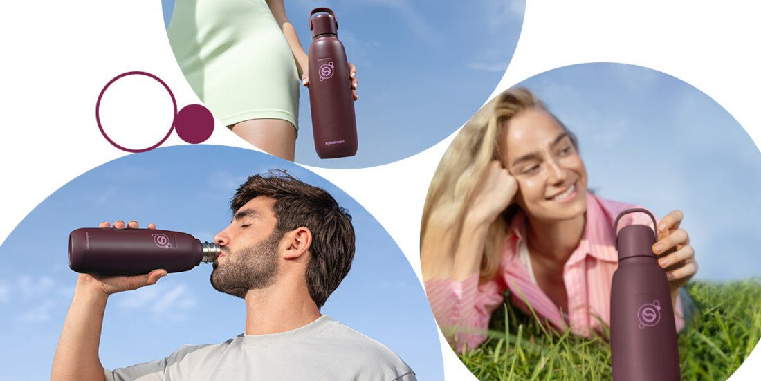 Na obrazie widoczna jest bordowa butelka termiczna z logo \'SODASTREAM\' trzymana przez osoby w różnych sytuacjach na tle nieba i trawy. Butelka ma smukły kształt i zakrętkę w tym samym kolorze.