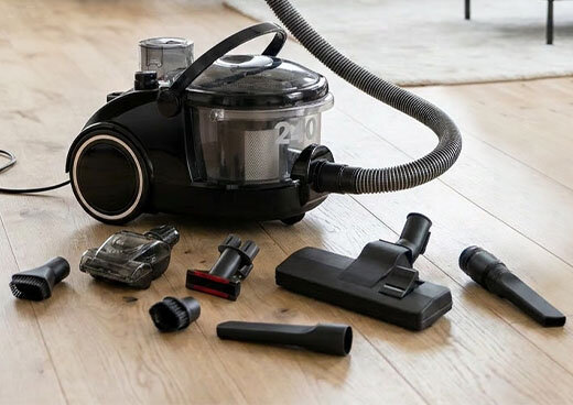 Odkurzacz z filtrem wodnym BORA 2400 MOD-47 stoi na podłodzę. Przed nim rozłożone są różne wymienne końcówki do urządzenia.