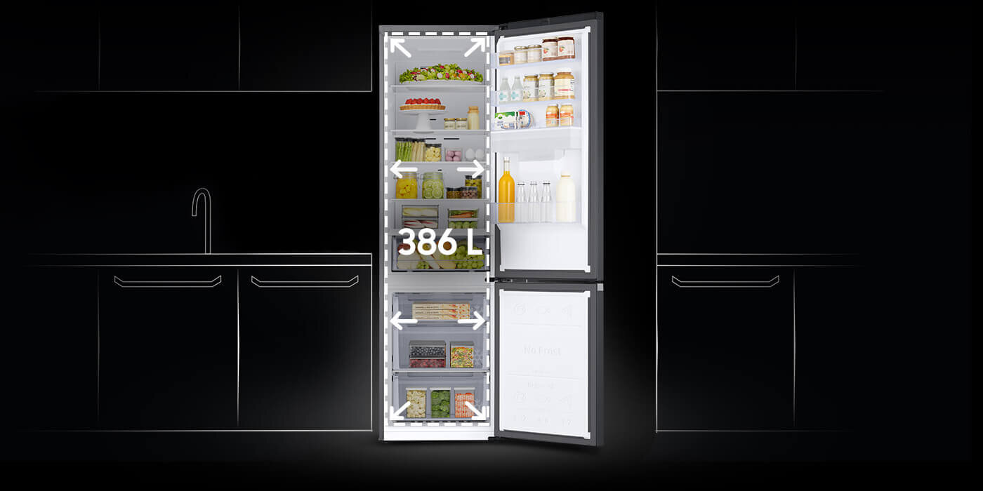 Pojemność lodówki Samsung Grand+ w technologii SpaceMax wynosi aż 390 litrów Otwarta lodówka z widocznymi półkami wypełnionymi różnymi produktami spożywczymi, na drzwiach znajdują się butelki i słoiki. Na lodówce widoczny jest napis \'386 L\'.