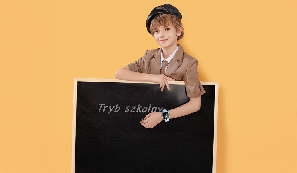 Osoba w brązowym stroju i czapce opiera się o tablicę z napisem \'Tryb szkolny\'. Na nadgarstku ma niebieski smartwatch.