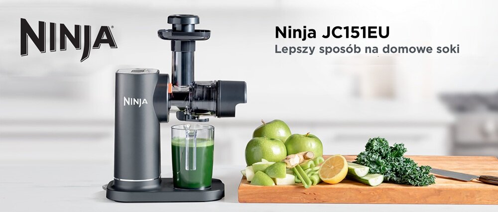 Na obrazie znajduje się wyciskarka wolnoobrotowa z logo Ninja, obok której stoi szklanka z zielonym sokiem. Obok na desce leżą zielone jabłka, cytryna i warzywa, a w tle widoczny jest napis \'Ninja JC151EU Lepszy sposób na domowe soki\'.