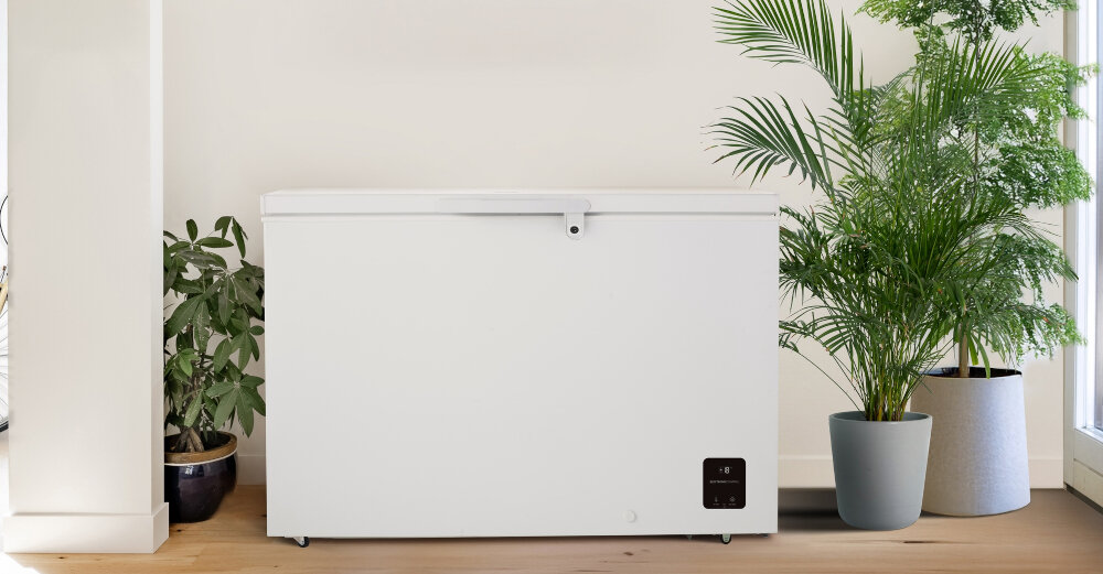 ZAMRAŻARKA GORENJE FH30DAW Biała zamrażarka skrzyniowa ustawiona w jasnym wnętrzu obok dużych roślin doniczkowych. W prawym dolnym rogu urządzenia widoczny jest panel sterowania z wyświetlaczem 297 l FastFreeze FreezeProtect sprężarka inwerterowa wyświetlacz LED dwa kosze oświetlenie LED zamek zabezpieczający cicha praca energooszczędność