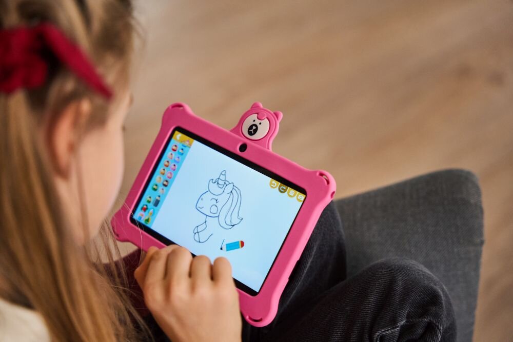 Dziecko trzyma różowy tablet z rysunkiem jednorożca na ekranie. Tablet ma ochronną obudowę z motywem misia.