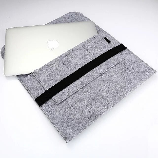 Szare filcowe etui na laptopa z czarnym paskiem, częściowo otwarte, z widocznym srebrnym laptopem z logo jabłka.