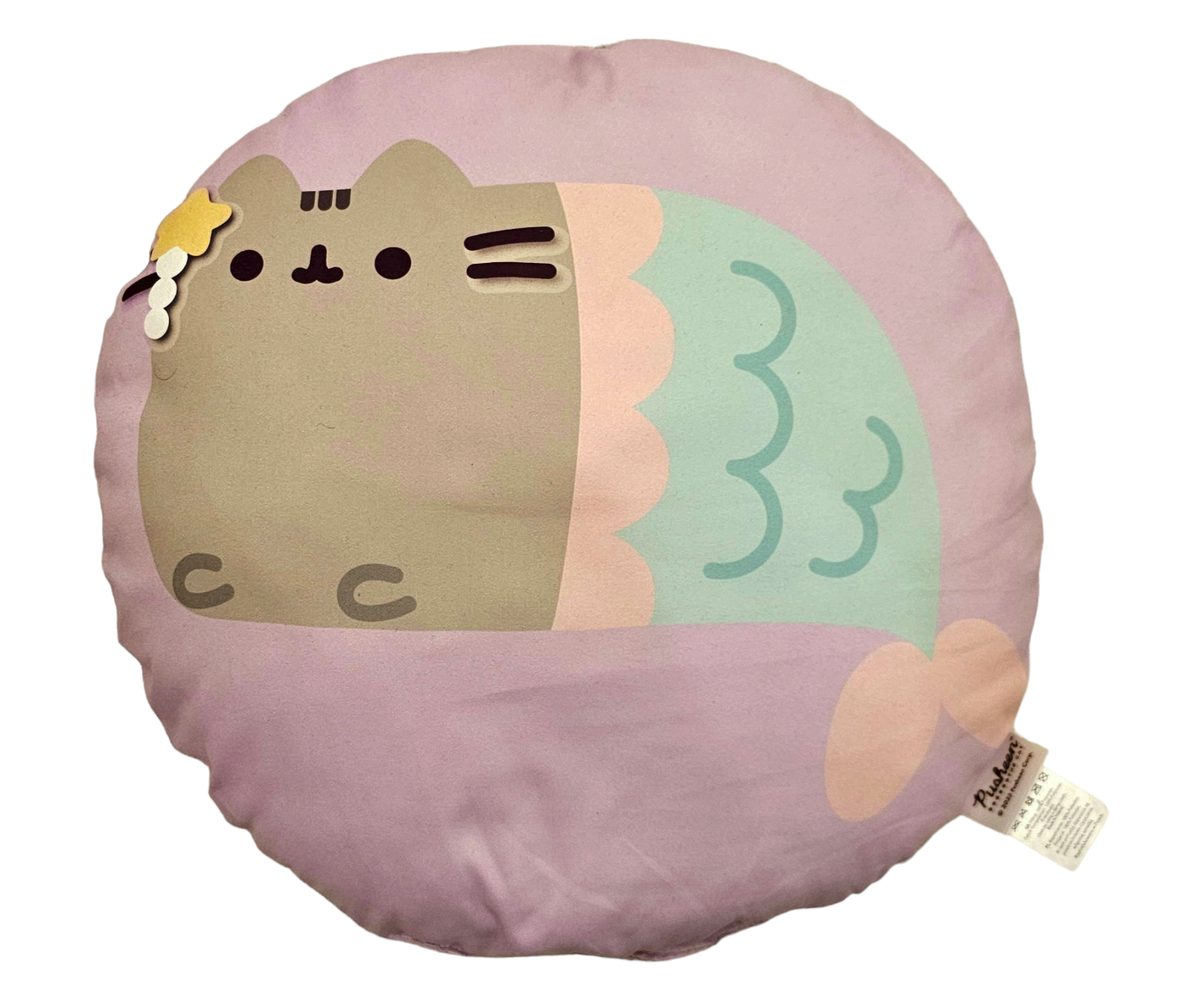 Poduszka w kształcie okrągłym z nadrukiem szarego kotka z ogonem syrenki na fioletowym tle. Na metce widoczny jest napis \'Pusheen\'.
